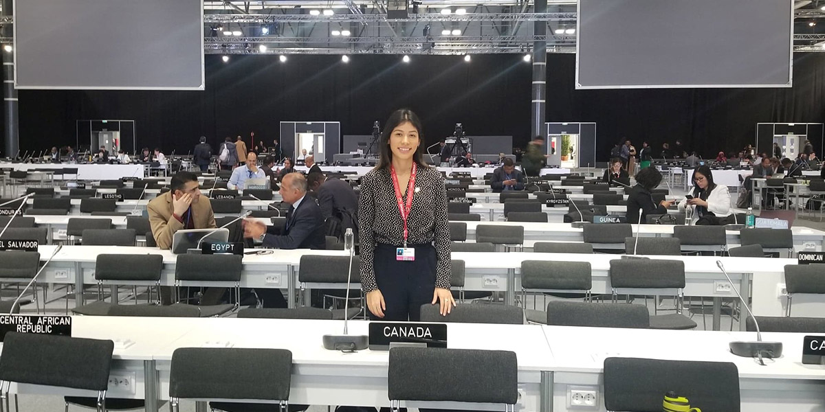 Maria standing behind a signed saying Canada