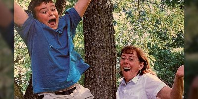 Kevin Southgate as a youth jumping ecstatically in the forest with his aunt in the background