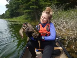 Amy Hall in a canoe holding a big turtle.
