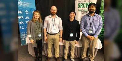 amy hall and three young men in front of PLT Canada conference booth