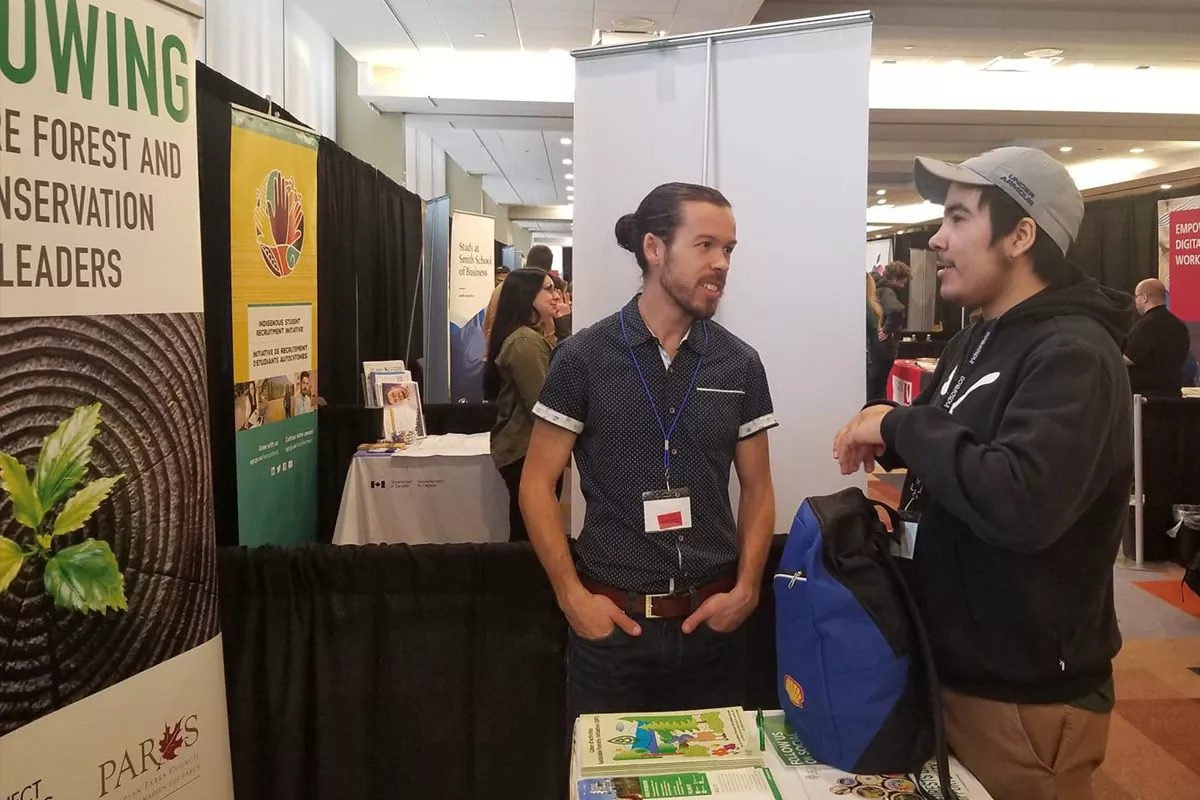 Paul speaks with a young Indigenous woman at the PLT Canada booth at Indspires 2020 Soaring event