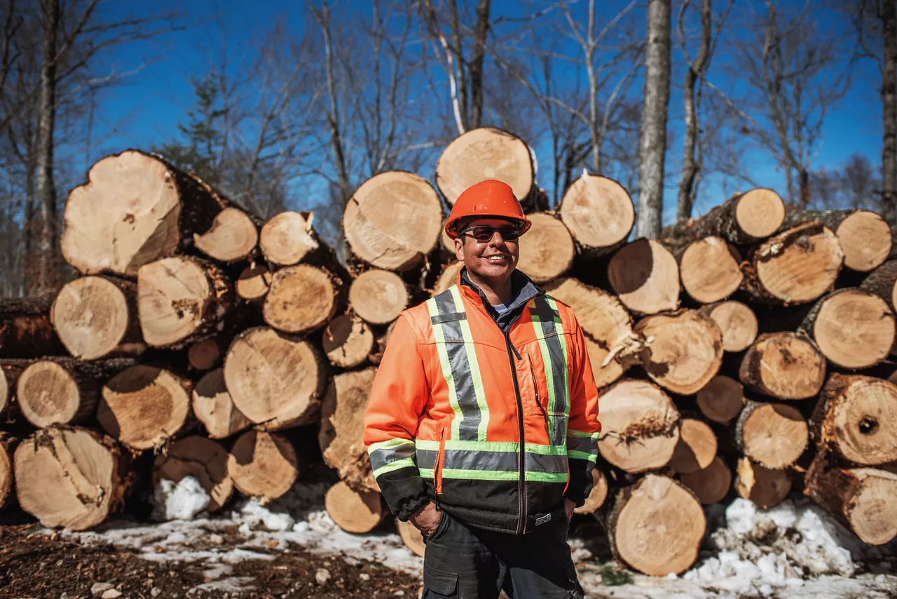 Dean standing in front of logs