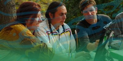 an indigenous man and woman work at a computer with a Caucasian man