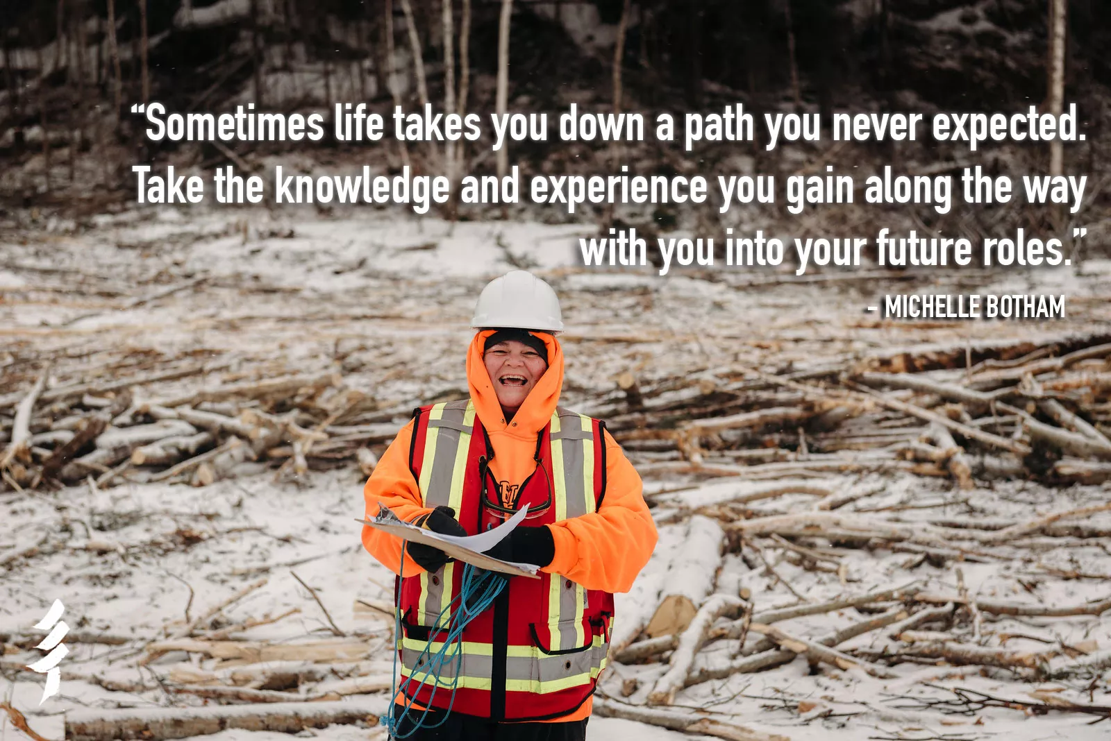 Michelle Botham, in a hard hat and high visibility clothing, holding papers in a recently harvest area of the forest
