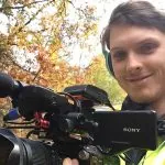 Young man holding a video camera in the forest