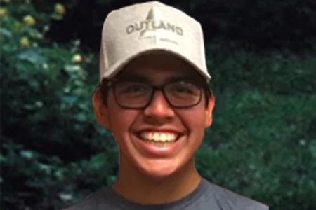 A young person smiling in an Outland baseball cap