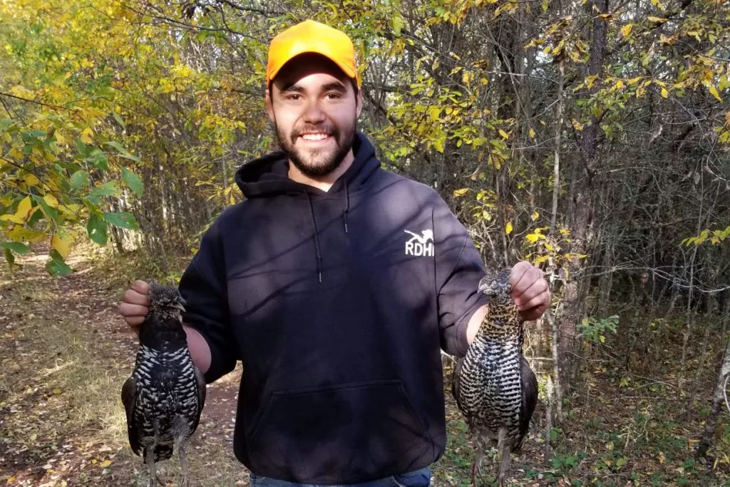 A young person holds two birds in each hand
