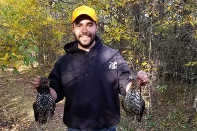 A young person holds two birds in each hand