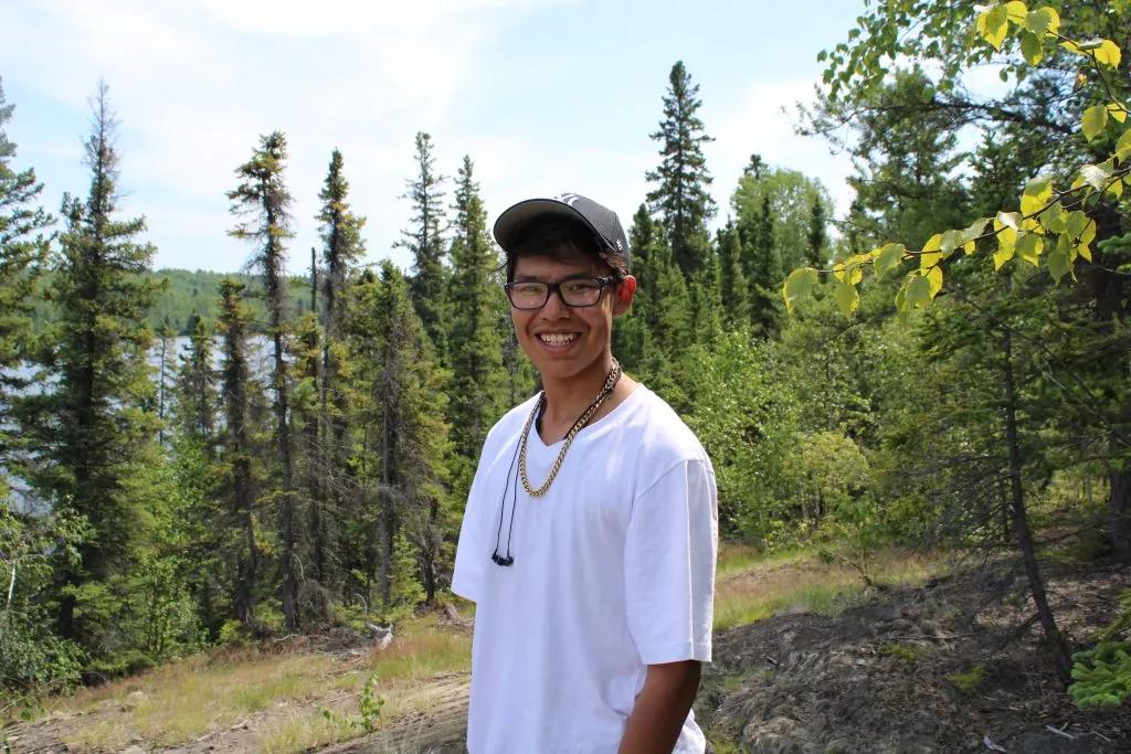 A young person smiling in a forest