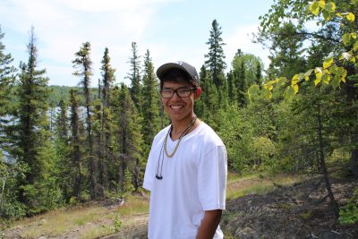 A young person smiling in a forest