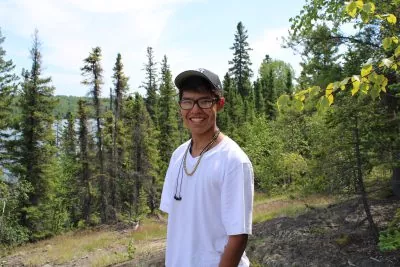 A young person smiling in a forest