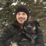 Mark Kmill holding a dog in the forest