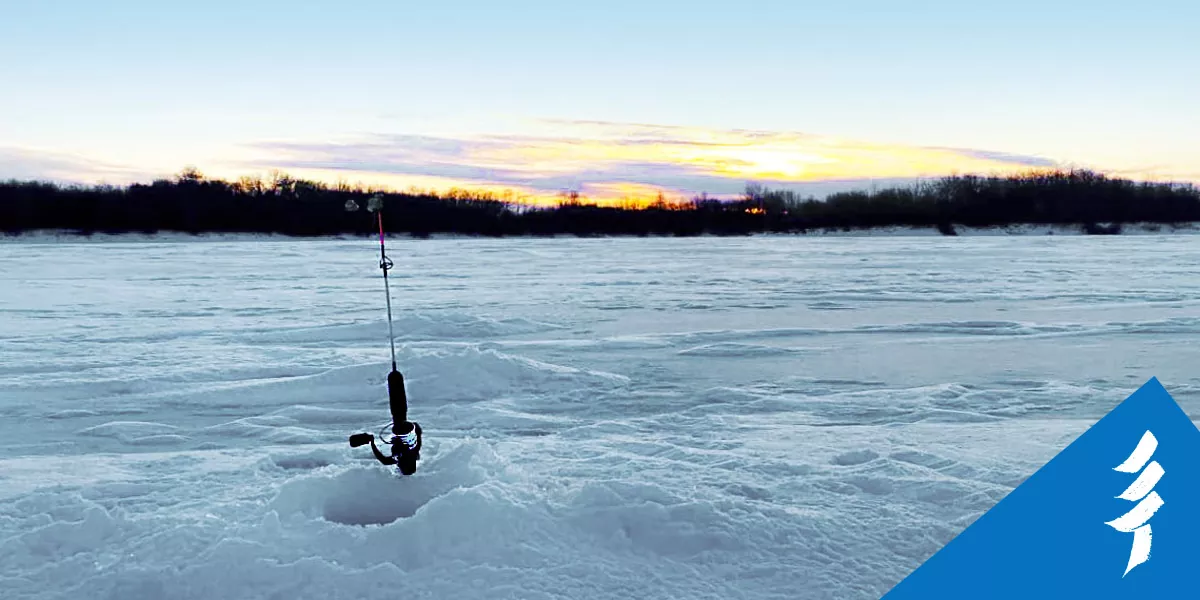 A fishing rod standing upright next to a hole in the ice.