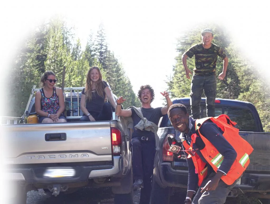 Youth hanging out in the forest with two pickup trucks