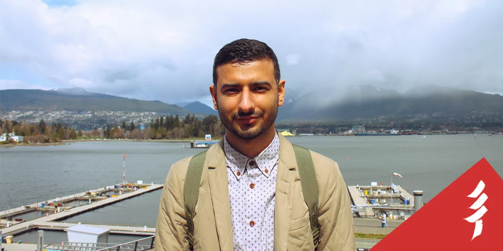 Ahmed looking at the camera, in front of docks and a body of water
