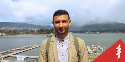 Ahmed looking at the camera, in front of docks and a body of water