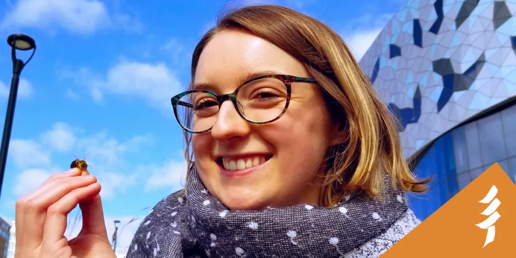 Sarah smiling at the camera with a bee resting on her hand