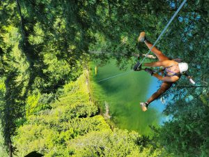 A young woman ziplining over a body of water