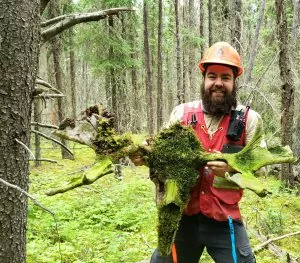 A young man in the forest holding a moose skull