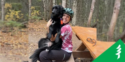 Emily Prouse sitting on a picnic table with a dog.