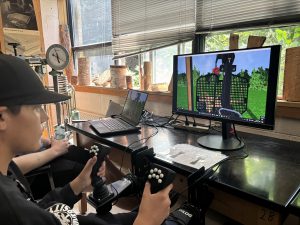 A young person hold the controls for the heavy equipment simulator.